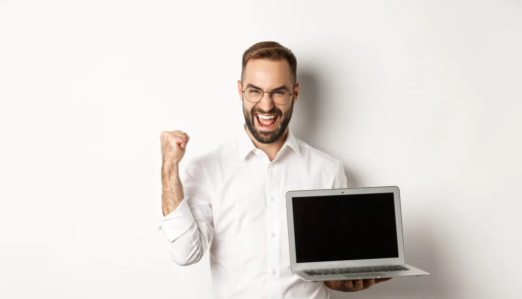 Homem comemorando com notebook em mãos